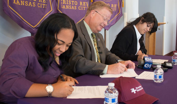 Cristo Rey students Alexus Williams, Samantha Ballesteros and Providence Medical Center CEO Randall Nyp signed an agreement that began the students’ work program at the hospital this year. 